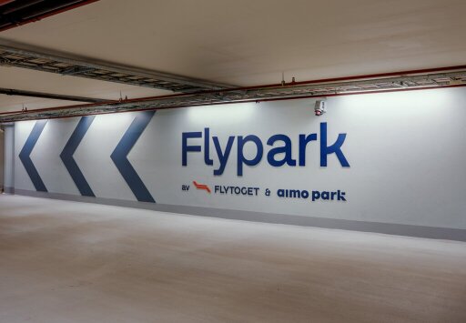 Bilde av stort vegghengt skilt i parkeringshus med teksten Flypark av Flytoget og Aimo Park