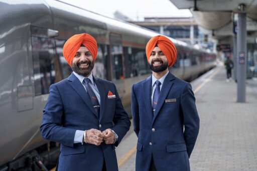 To Flytoget-ansatte iført oransje turban